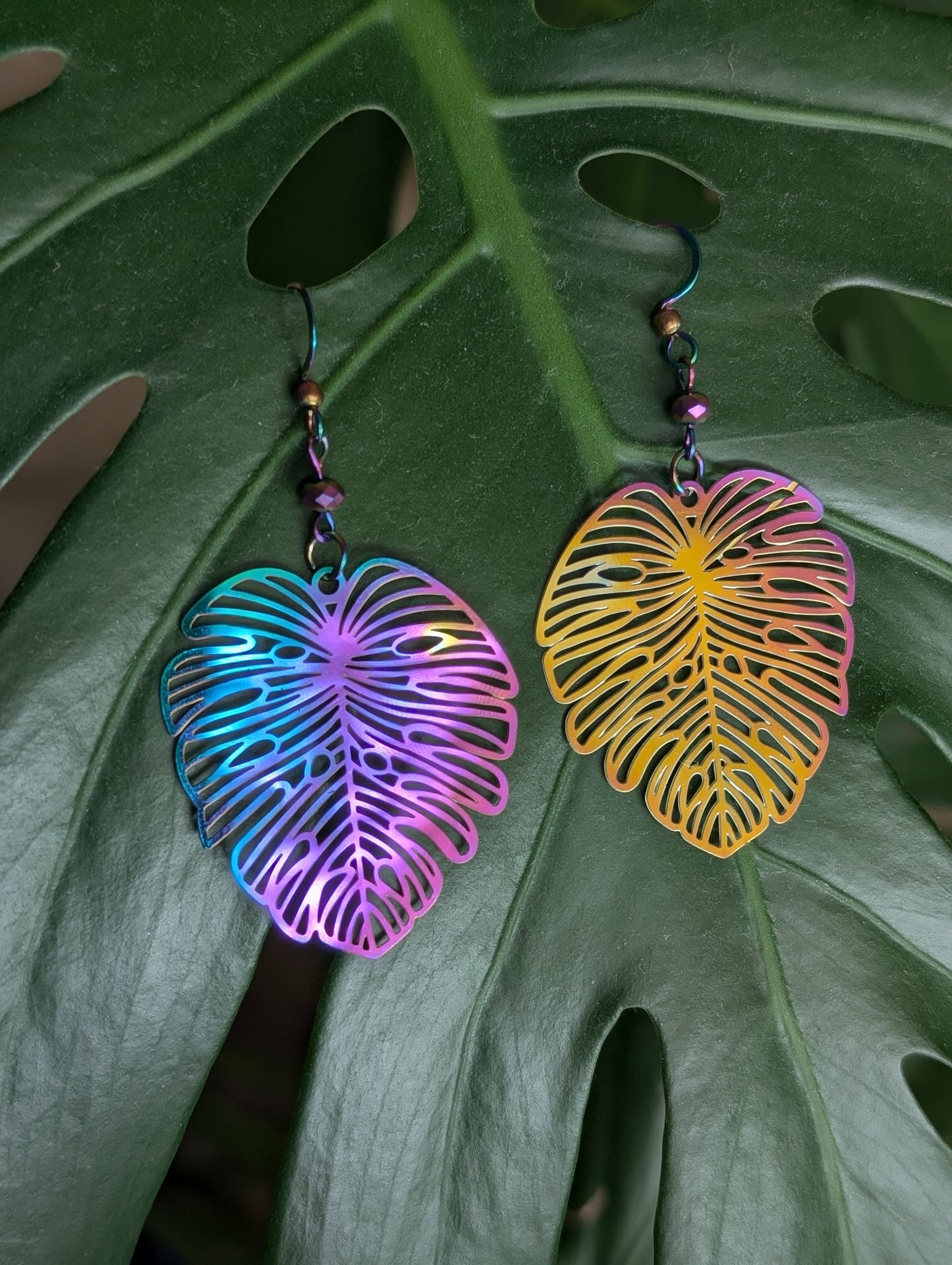 Lightweight rainbow Monstera dangling earrings, rainbow anodized stainless steel. Handcrafted by Cappa Creations, made of stainless steel, making them the highest quality, waterproof, tarnish proof, hypoallergenic, and nickel free! 

Perfect to wear on a beautiful summer day or  the sweetest gift for any plant lover! 