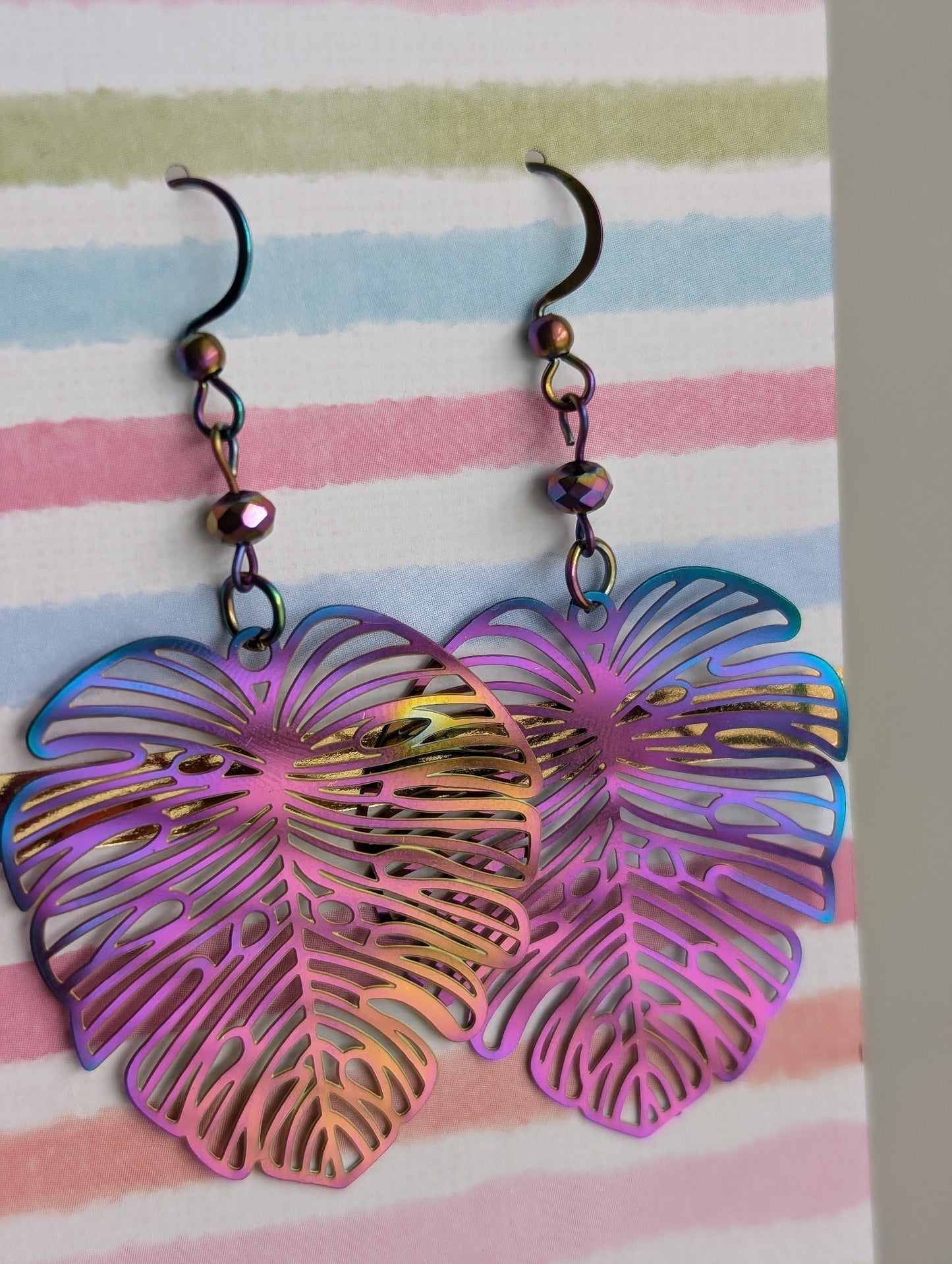 Lightweight rainbow Monstera dangling earrings, rainbow anodized stainless steel. Handcrafted by Cappa Creations, made of stainless steel, making them the highest quality, waterproof, tarnish proof, hypoallergenic, and nickel free! 

Perfect to wear on a beautiful summer day or  the sweetest gift for any plant lover! 