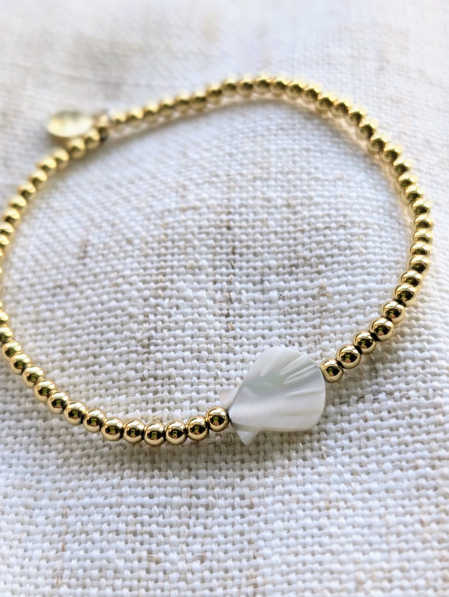 Scalloped Shell Gold Bracelet with 18k gold-filled beads and a hand-cut mother-of-pearl shell, styled on a clean background.