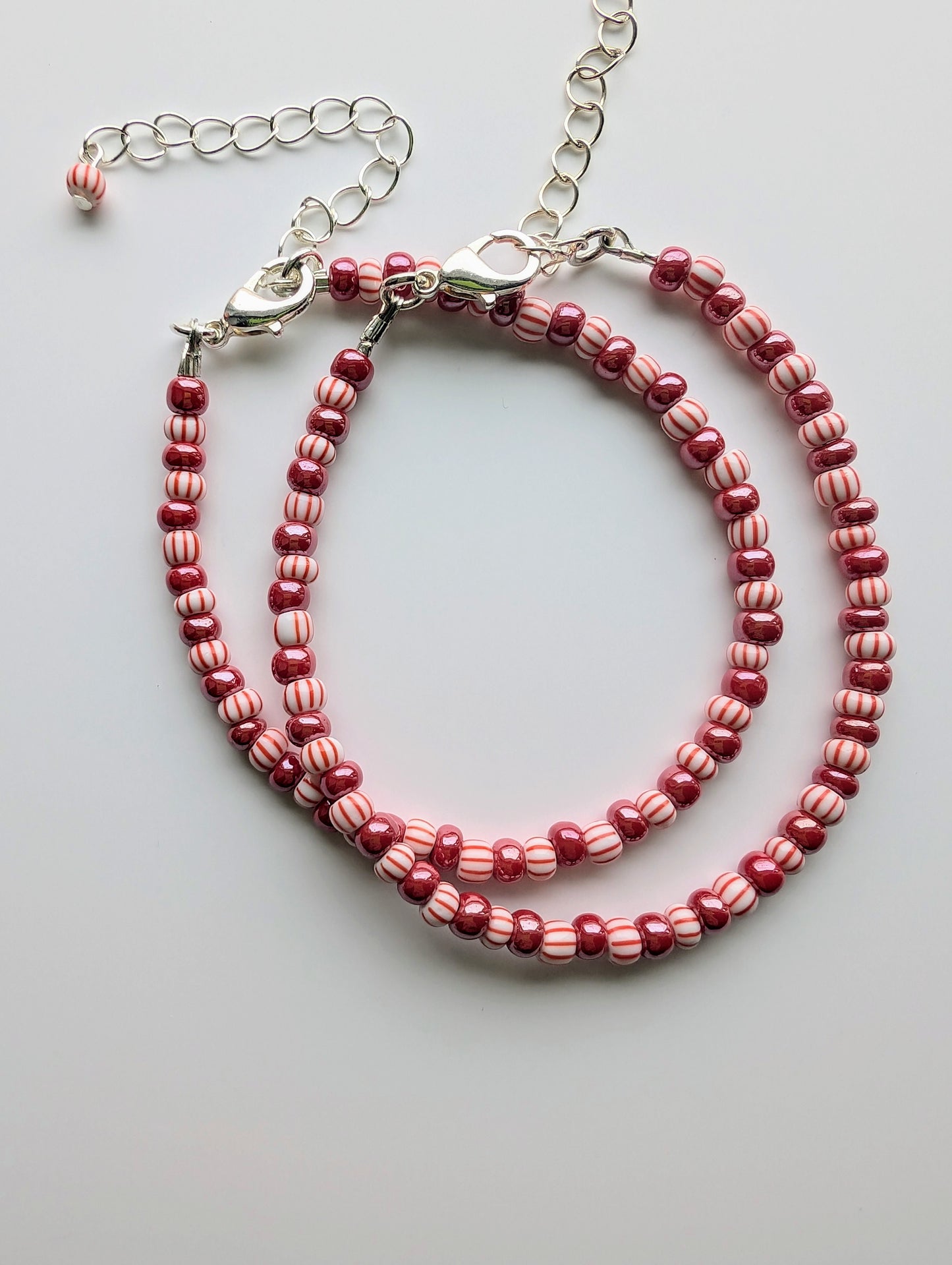 Cappa Creations Peppermint Party Bracelet with festive peppermint and pearly red beads, adjustable clasp, and sterling silver or 18K gold-plated chain extender for a cute holiday style.