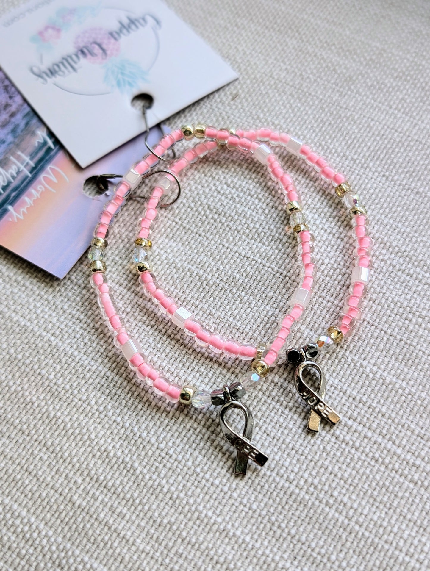 Breast Cancer Ribbon Charm Bracelet with pink seed beads and a silver hope ribbon charm, symbolizing support and strength.